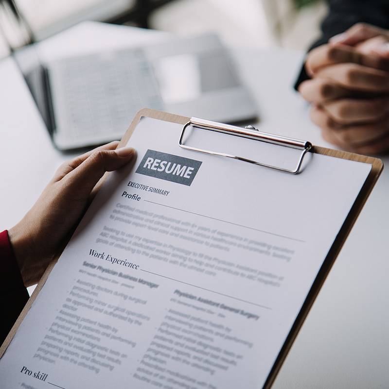 Businessman or job seeker review his resume on his desk before send to finding a new job with pen, necktie, glasses and digital tablet.